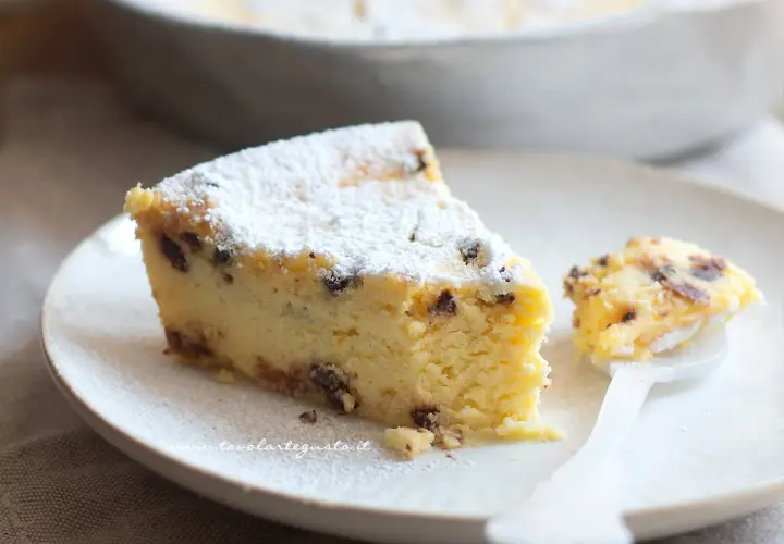 Una fetta di torta ricotta veloce, soffice e cosparsa di zucchero a velo, con gocce di cioccolato. Un assaggio delizioso.