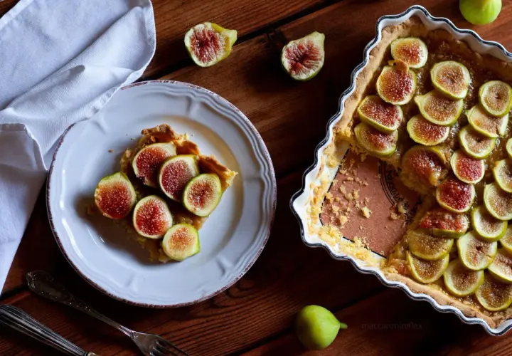 Deliziosi dolci con fichi freschi, una fetta su un piatto bianco e la torta intera in una teglia.