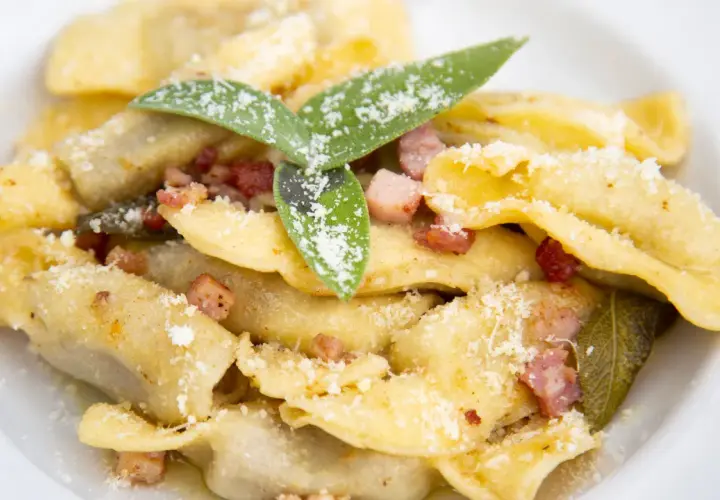 Un piatto di casoncelli alla bergamasca, conditi con burro, salvia e pancetta croccante, spolverati di parmigiano.