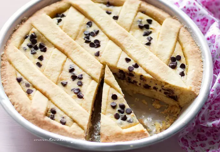 Una deliziosa crostata di ricotta con gocce di cioccolato, con una fetta tagliata per mostrare il ripieno cremoso.