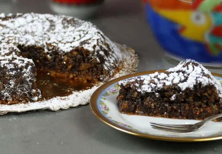 Torta Caprese, ricetta originale napoletana, con una fetta servita su un piatto decorato.