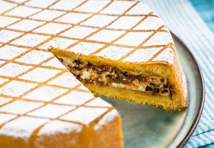 Una fetta di cassata al forno, con glassa a rombi e ripieno cremoso, pronta per essere gustata.
