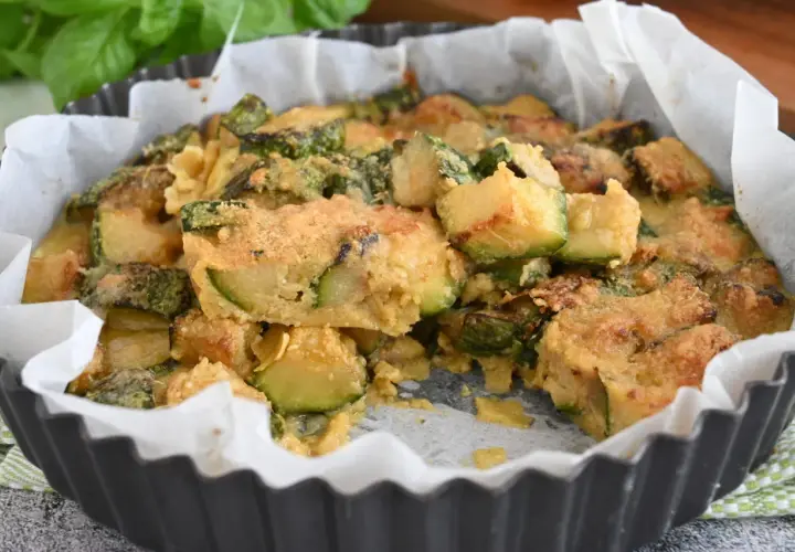 Deliziosi zucchine al forno, dorati e fragranti, in una tortiera foderata di carta forno.
