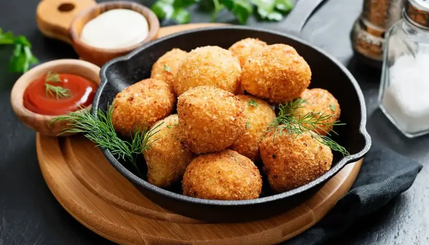 Croccanti polpette di zucca dorate servite in una padella di ghisa, con salse e erbe aromatiche.
