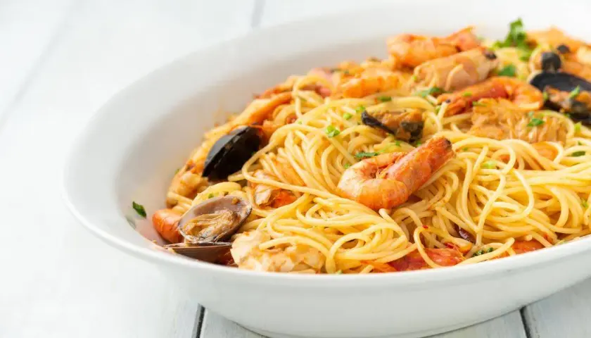 Un invitante piatto di spaghetti allo scoglio, ricco di gamberi, cozze e vongole, pronto per essere gustato.