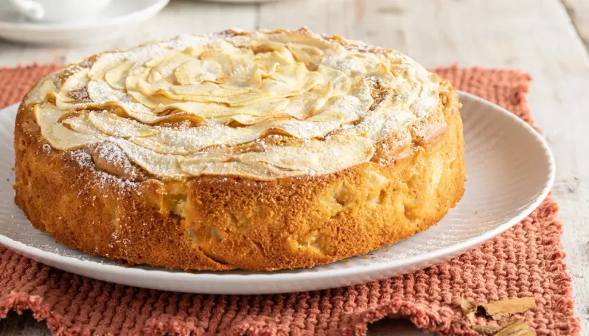 Una deliziosa torta di mele senza burro, decorata con fettine di mela e zucchero a velo, pronta per essere gustata.