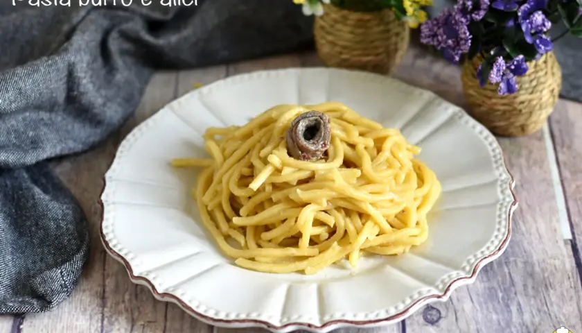 Un piatto di pasta burro e alici, semplice e gustoso, con un'alice arrotolata in cima.