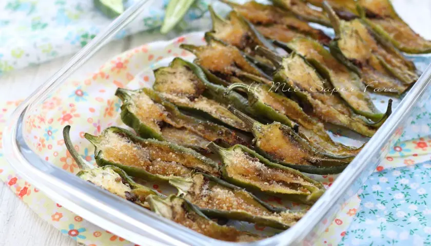 Friggitelli al forno, tagliati a metà e conditi con pangrattato e formaggio, pronti per essere gustati.