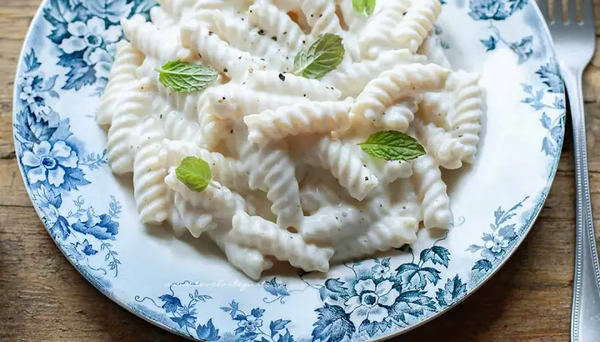 Fusilli cremosi con salsa alla ricotta, guarniti con menta fresca. Un'idea semplice per le tue ricette di pasta con ricotta.