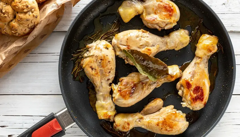 Fusi di pollo succulenti e dorati in padella, con rosmarino e alloro. Accompagnati da panini integrali.