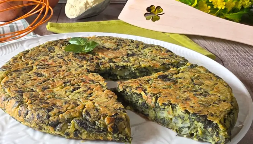 Frittata di spinaci dorata e soffice, guarnita con basilico fresco, pronta per essere gustata.