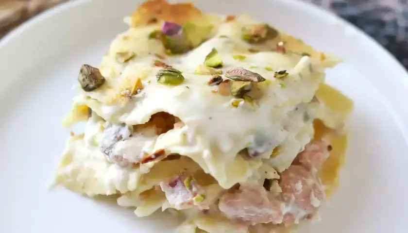Un invitante primo piatto della domenica: lasagna cremosa con ragù rosa e pistacchi croccanti.