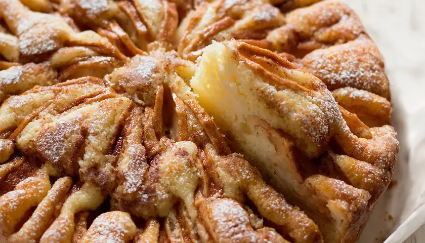 Una deliziosa torta di mele, con fette di mela disposte a raggiera e spolverata di zucchero a velo.