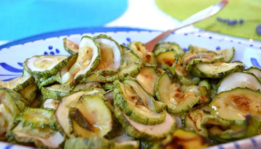 Fette di zucchine in carpione, condite con olio e aceto, pronte per essere gustate.