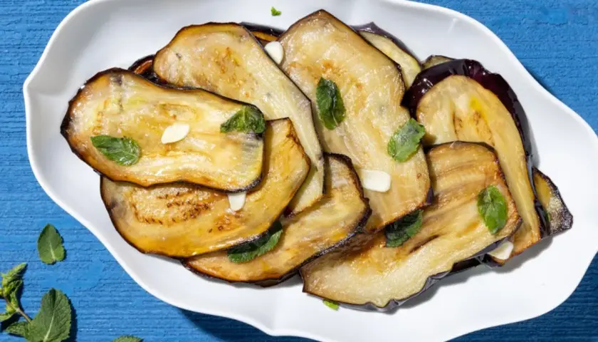 Fette di melanzane grigliate, condite con aglio e menta, un contorno di verdure saporito e colorato.