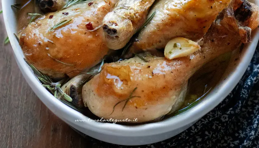Succulente sovracosce di pollo al forno, dorate e profumate con aglio e rosmarino, servite in una ciotola bianca.