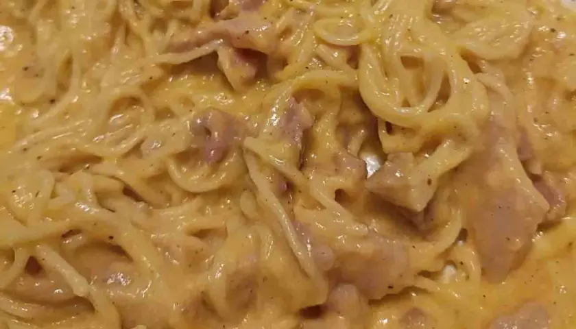 Un piatto cremoso di pasta alla carbonara, con spaghetti avvolti in una salsa dorata e pezzetti di guanciale.