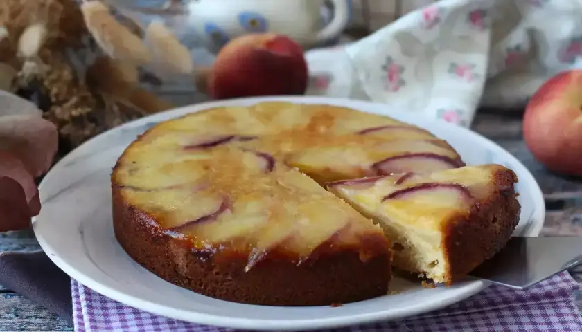 Deliziosa torta di pesche rovesciata, con fette dorate e succose che invitano ad assaggiare.