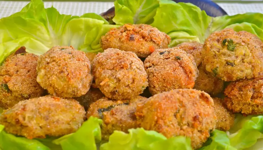 Polpette di melanzane fritte dorate e croccanti, servite su un letto di lattuga fresca.