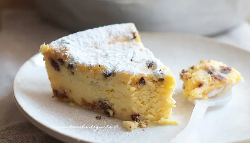 Una fetta di torta ricotta veloce, soffice e cosparsa di zucchero a velo, con gocce di cioccolato. Un assaggio delizioso.