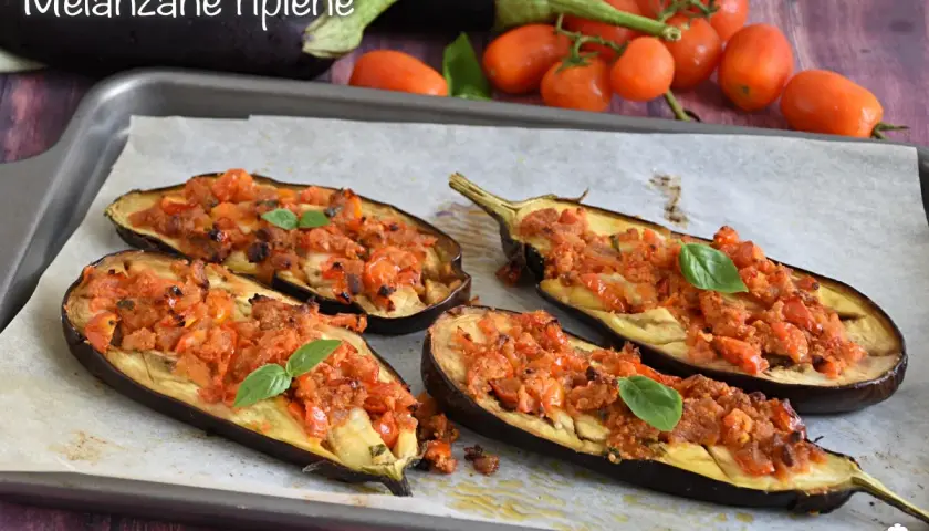 Melanzane ripiene senza carne, un piatto saporito e colorato, con pomodorini e basilico fresco.