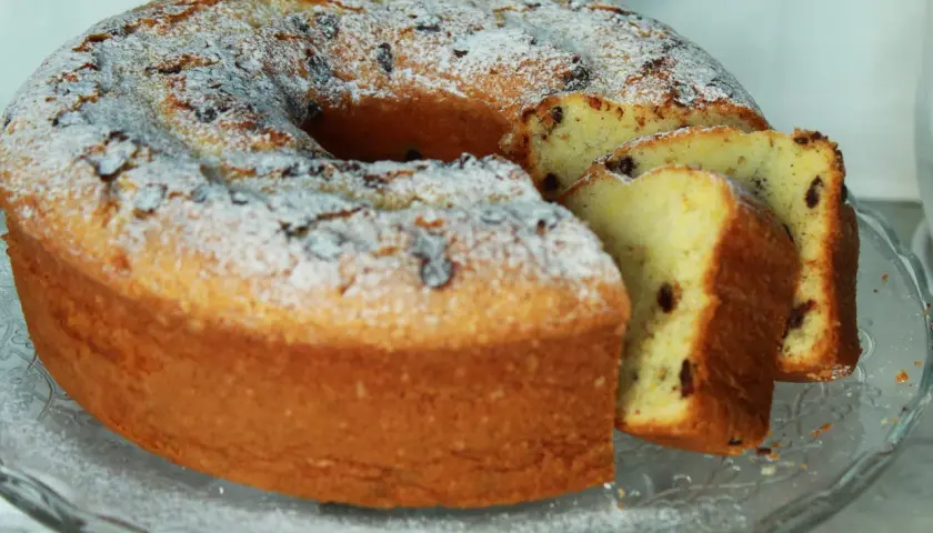 Ciambellone soffice con tante gocce di cioccolato, spolverato di zucchero a velo, pronto per essere gustato.