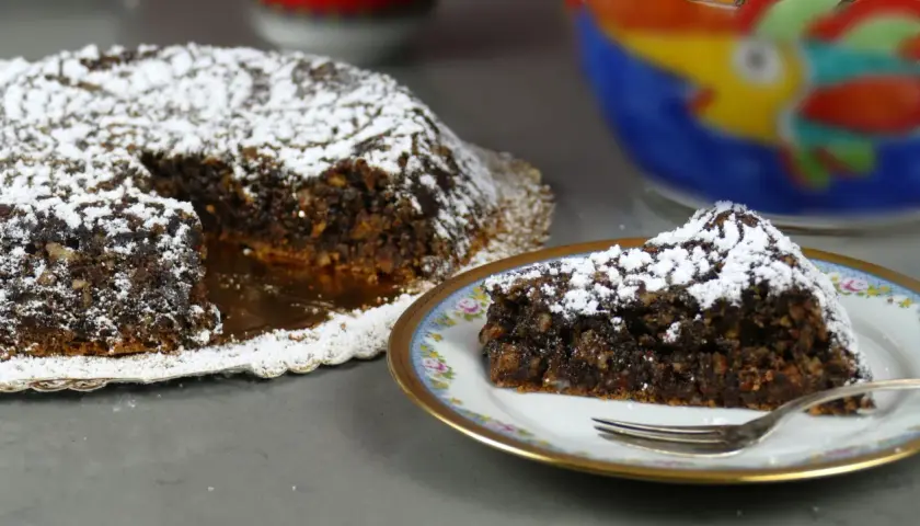 Torta Caprese, ricetta originale napoletana, con una fetta servita su un piatto decorato.