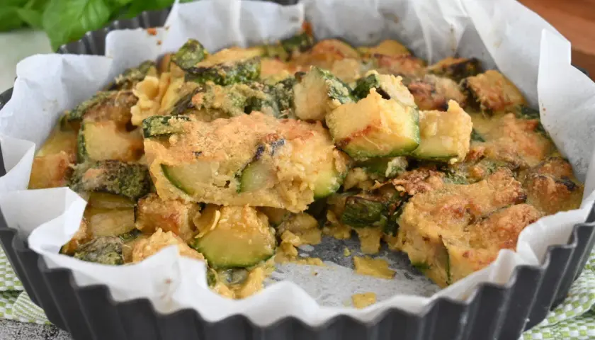 Deliziosi zucchine al forno, dorati e fragranti, in una tortiera foderata di carta forno.