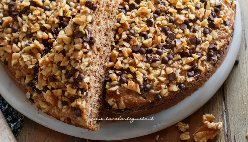 Torta di noci della nonna, soffice e golosa, ricoperta di noci tritate e gocce di cioccolato. Un classico intramontabile.