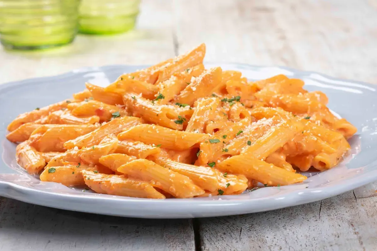 Penne cremose con salsa rosa, un piatto di pasta veloce e sfiziosa, guarnito con prezzemolo e parmigiano.