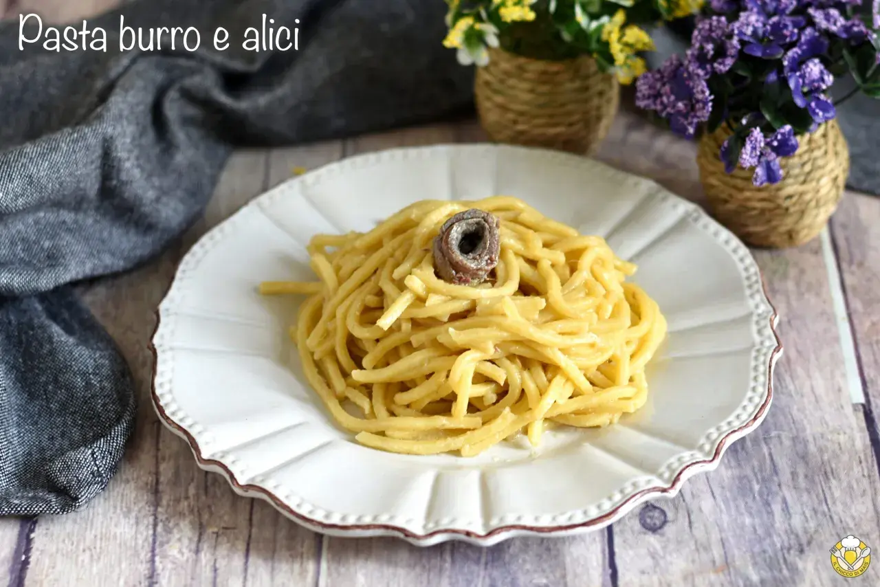 Un piatto di pasta burro e alici, semplice e gustoso, con un'alice arrotolata in cima.
