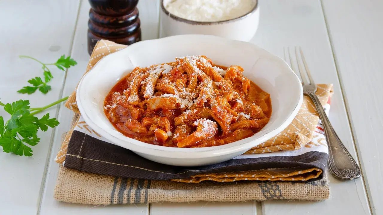 Un invitante piatto di trippa alla parmigiana, cosparso di formaggio grattugiato, pronto per essere gustato.