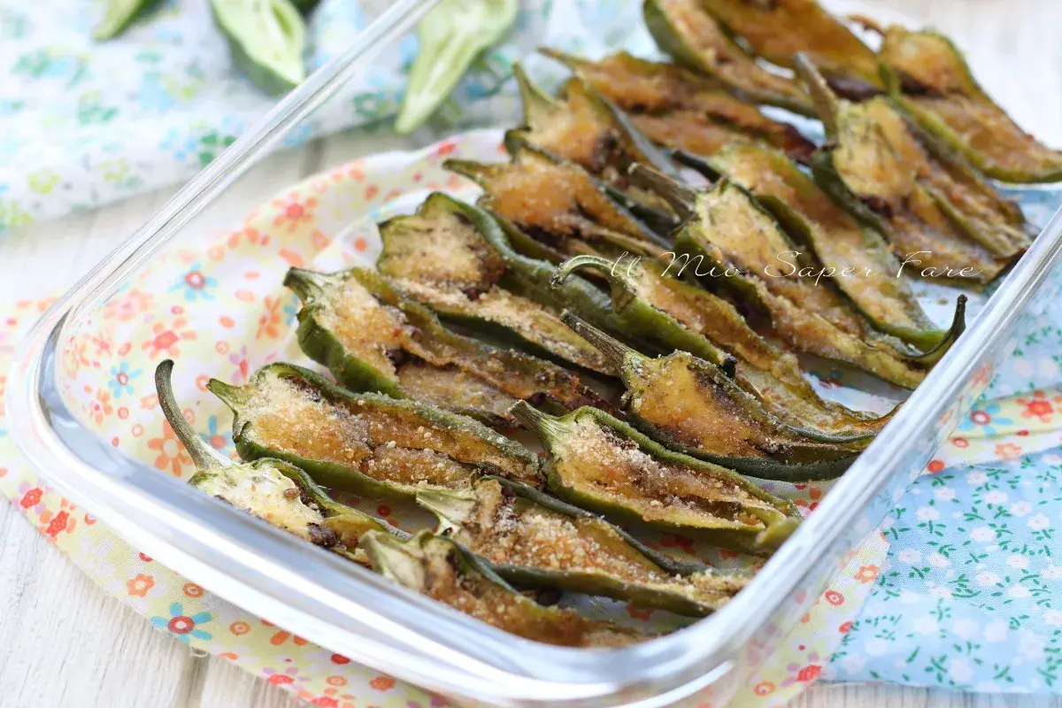 Friggitelli al forno, tagliati a metà e conditi con pangrattato e formaggio, pronti per essere gustati.
