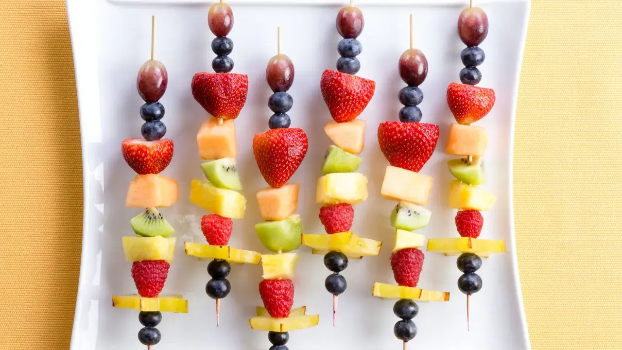 Spiedini di frutta colorati, perfetti per idee fresche e golose. Fragole, kiwi, melone e mirtilli su stecchini.