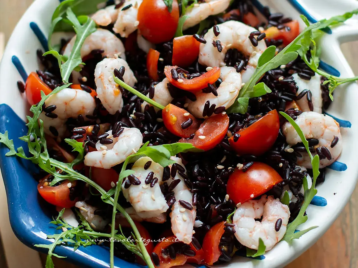 Riso Venere freddo con gamberetti, pomodorini e rucola, un piatto fresco e colorato.