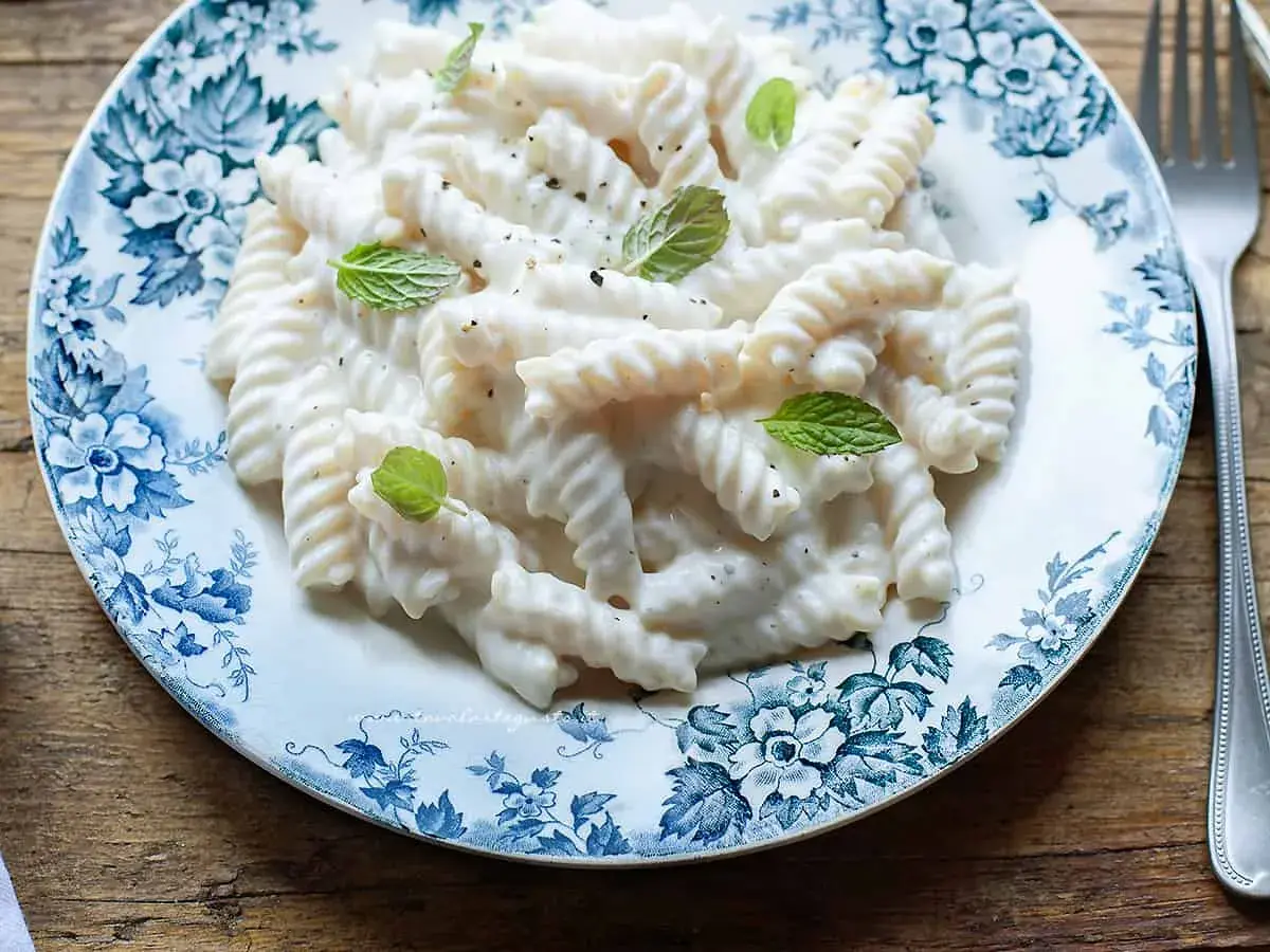Fusilli cremosi con salsa alla ricotta, guarniti con menta fresca. Un'idea semplice per le tue ricette di pasta con ricotta.