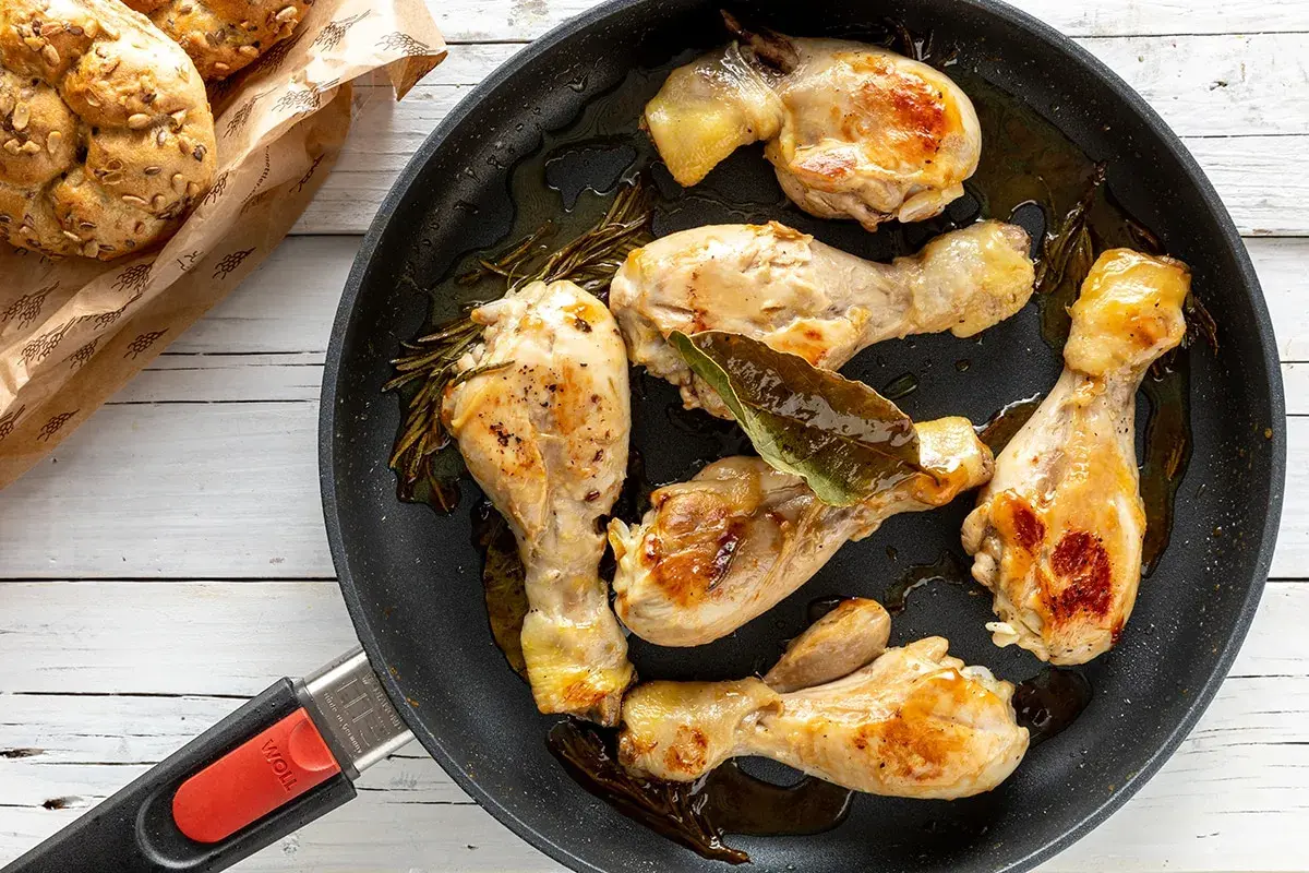 Fusi di pollo succulenti e dorati in padella, con rosmarino e alloro. Accompagnati da panini integrali.