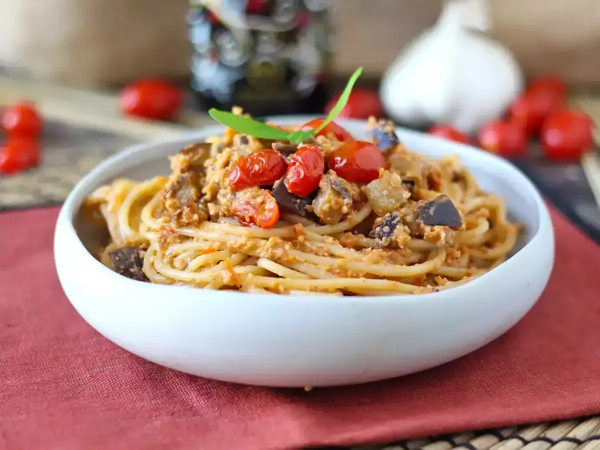 Un piatto invitante di pasta e melanzane alla napoletana, condito con pomodorini freschi e basilico.