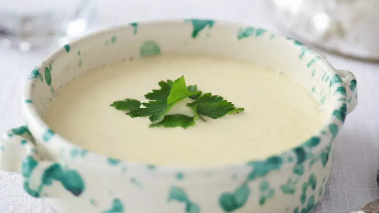 Una ciotola decorata con una vellutata crema di parmigiano, guarnita con prezzemolo fresco.