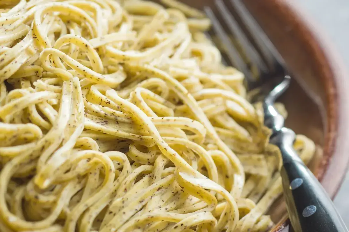 Un primo piatto invitante: tagliolini al limone, conditi con una crema delicata e erbe aromatiche, pronti per essere gustati con una forchetta.