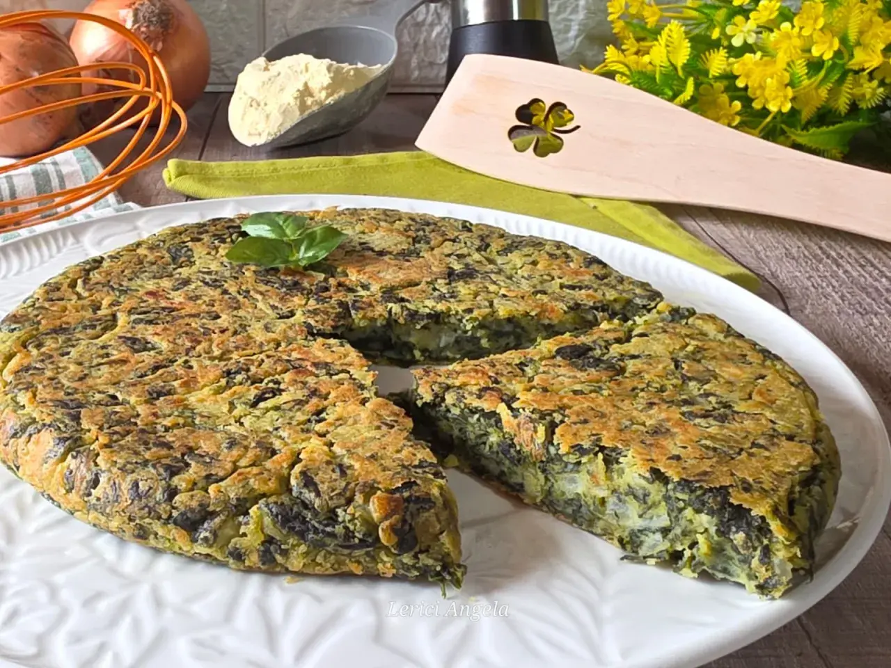 Frittata di spinaci dorata e soffice, guarnita con basilico fresco, pronta per essere gustata.