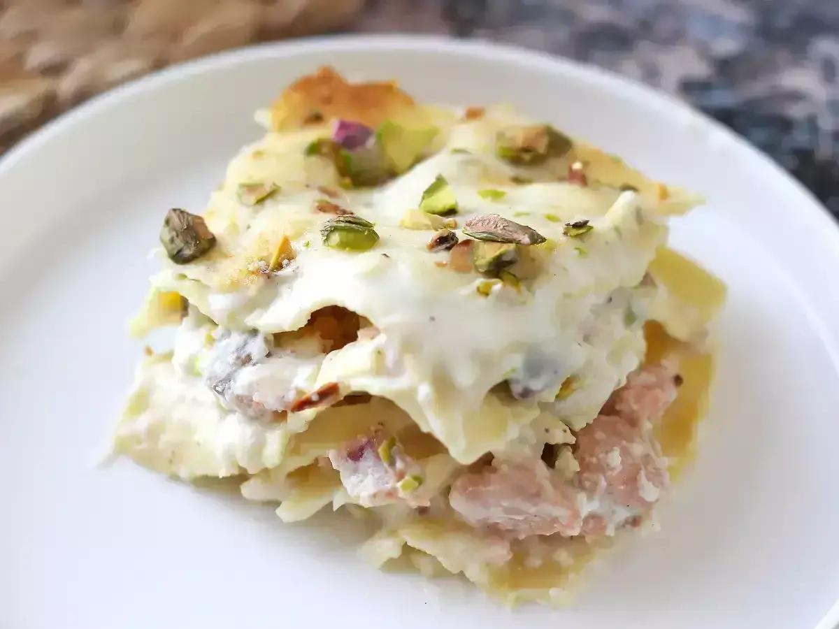 Un invitante primo piatto della domenica: lasagna cremosa con ragù rosa e pistacchi croccanti.
