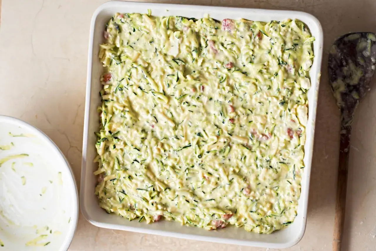 Sformato di zucchine pronto per essere infornato, con zucchine grattugiate e un cremoso impasto.