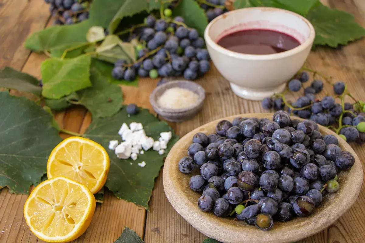 Uva fragola fresca, limone, zucchero e una ciotola di succo scuro, ingredienti per una deliziosa marmellata.