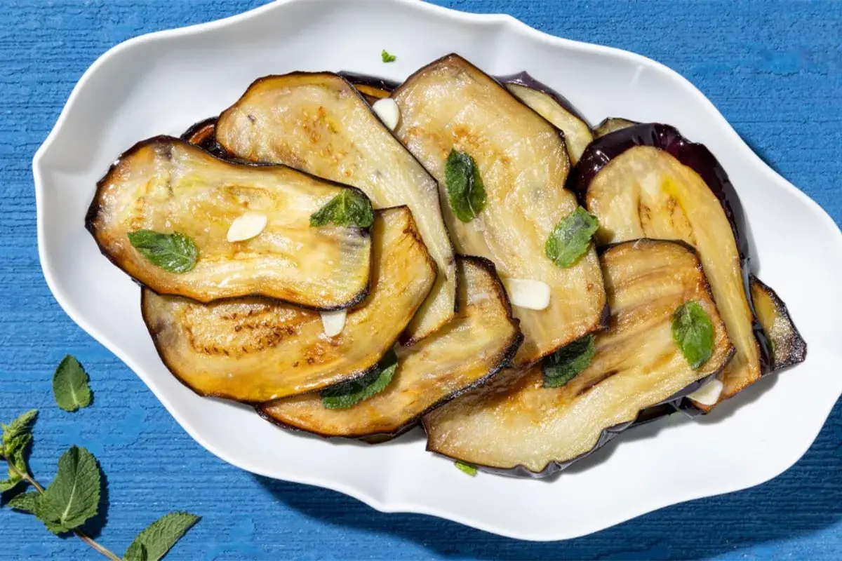 Fette di melanzane grigliate, condite con aglio e menta, un contorno di verdure saporito e colorato.