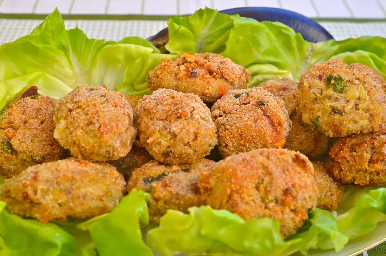 Polpette di melanzane fritte dorate e croccanti, servite su un letto di lattuga fresca.