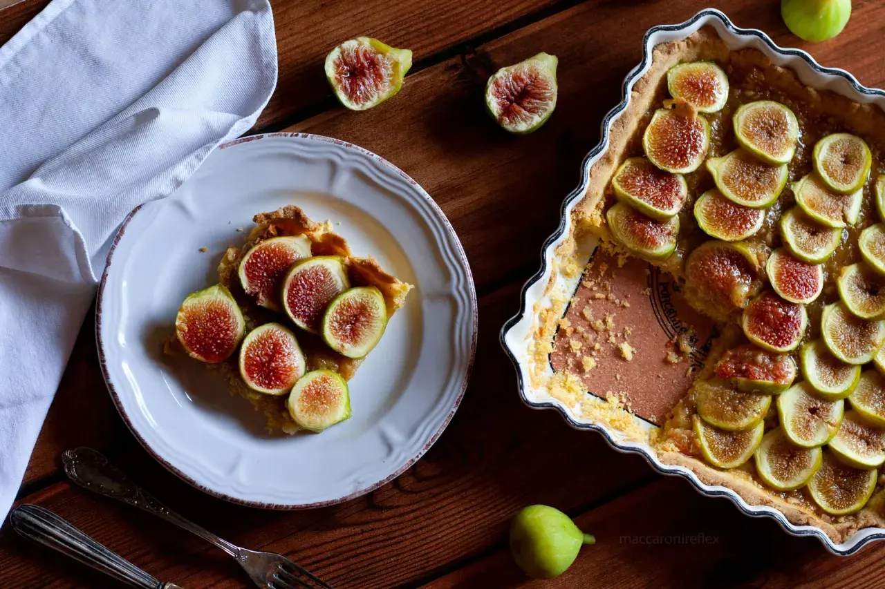 Deliziosi dolci con fichi freschi, una fetta su un piatto bianco e la torta intera in una teglia.