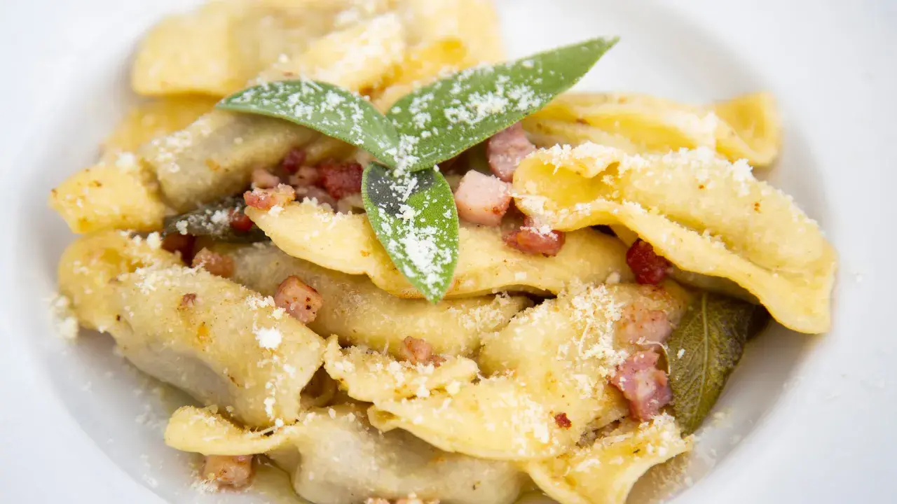 Un piatto di casoncelli alla bergamasca, conditi con burro, salvia e pancetta croccante, spolverati di parmigiano.