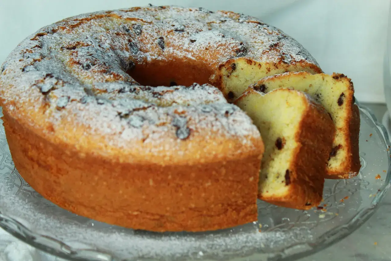 Ciambellone soffice con tante gocce di cioccolato, spolverato di zucchero a velo, pronto per essere gustato.