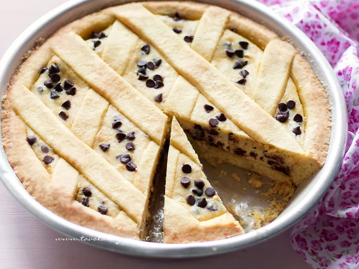 Una deliziosa crostata di ricotta con gocce di cioccolato, con una fetta tagliata per mostrare il ripieno cremoso.